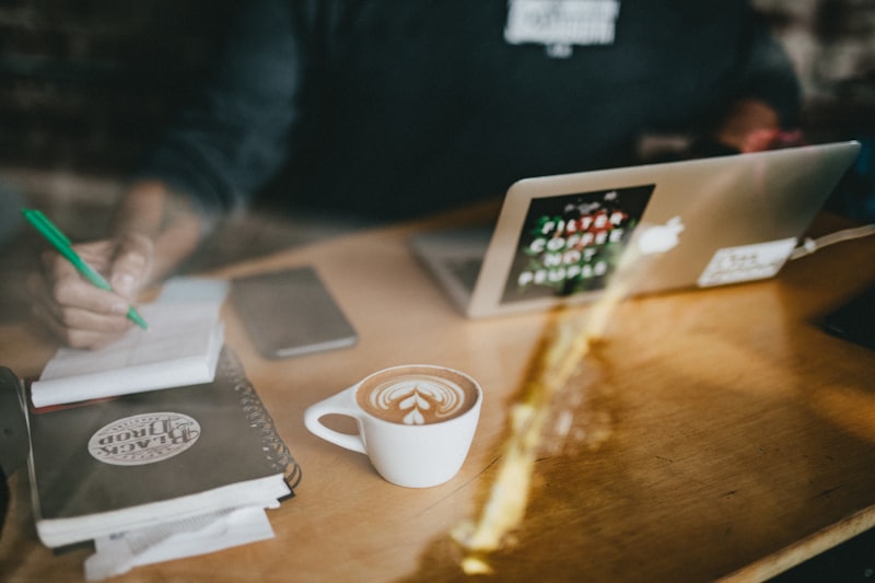 Person working on a laptop with a coffee and documents nearby